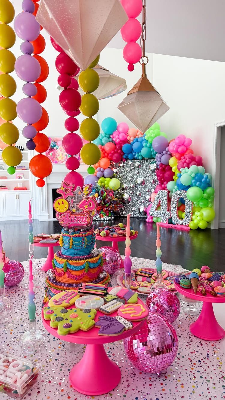 Multi-colored balloons and pink cake stands with sweets for a 40th birthday party.