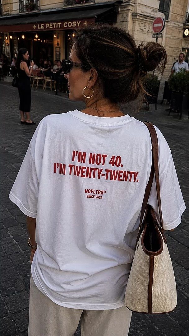 Woman wearing a white t-shirt with red text about being twenty-twenty instead of 40.