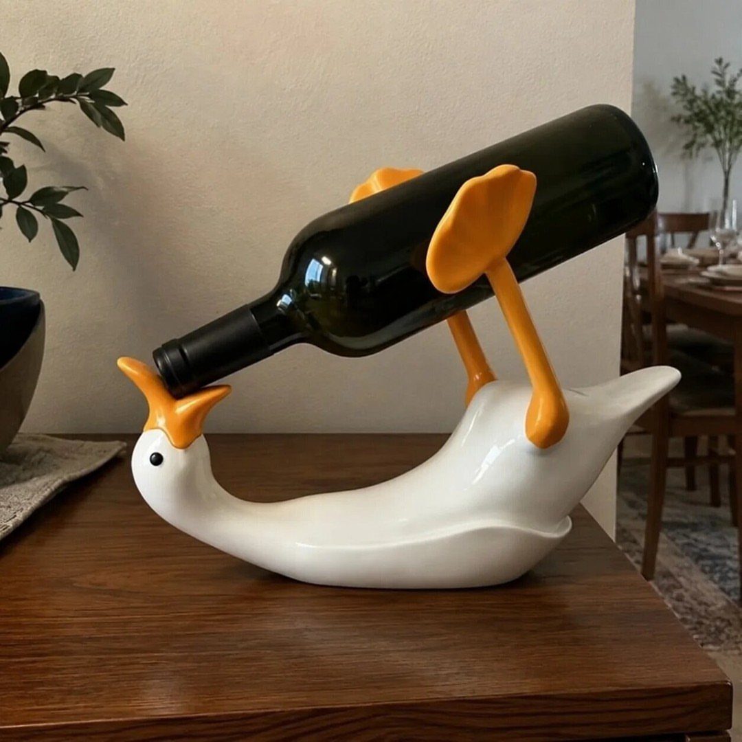 White ceramic goose wine holder supporting a dark green wine bottle on a table