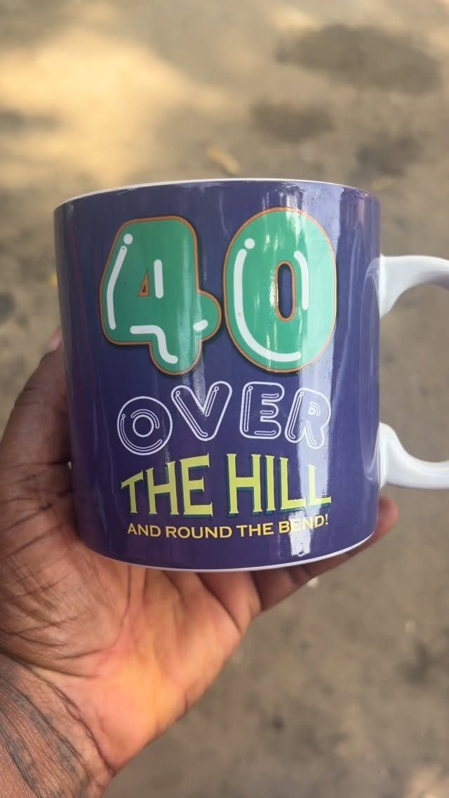 Purple ceramic mug with 40 over the hill text held in a hand