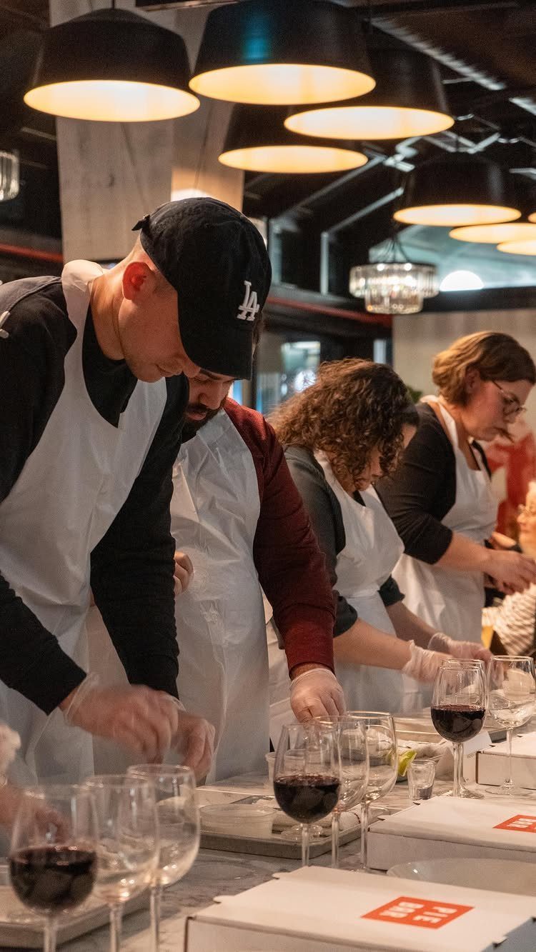 People in white aprons preparing food and red wine at a restaurant counter