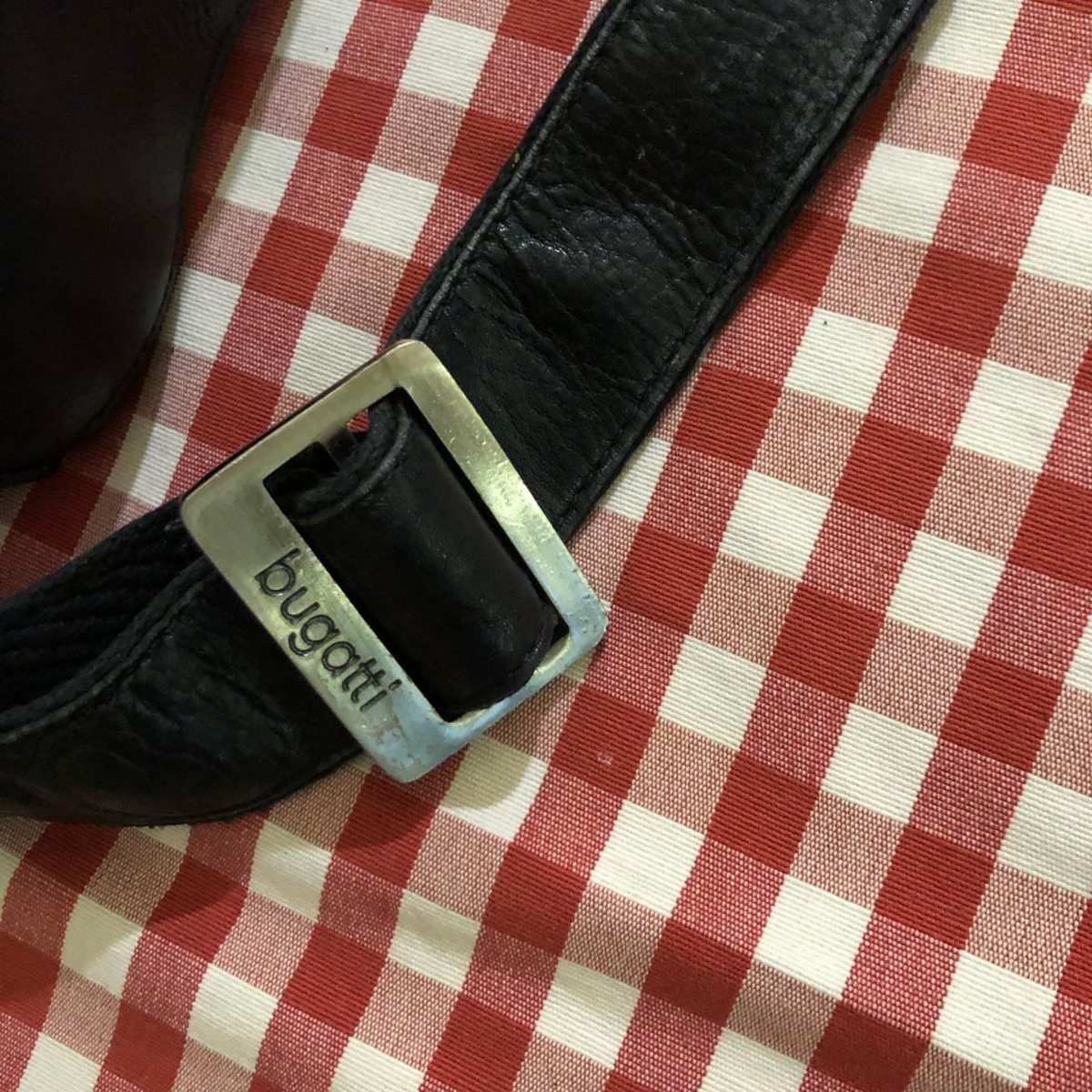 Black leather Bugatti belt with silver buckle on red and white checkered cloth