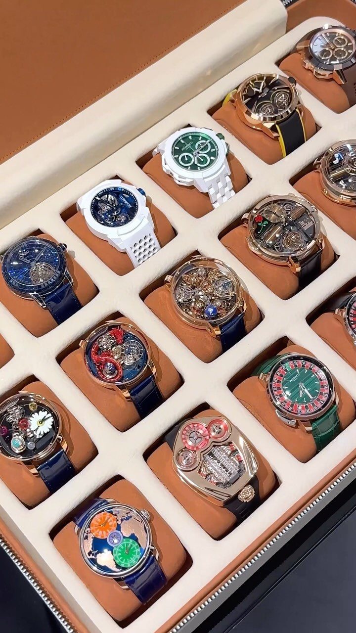 Luxury wristwatches in various colors displayed in a white leather organizer box