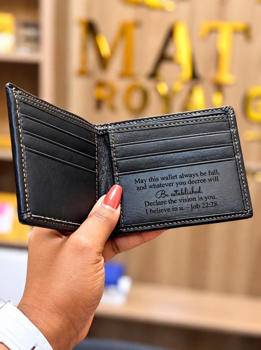 Black leather bifold wallet held open showing an engraved message on the inside.
