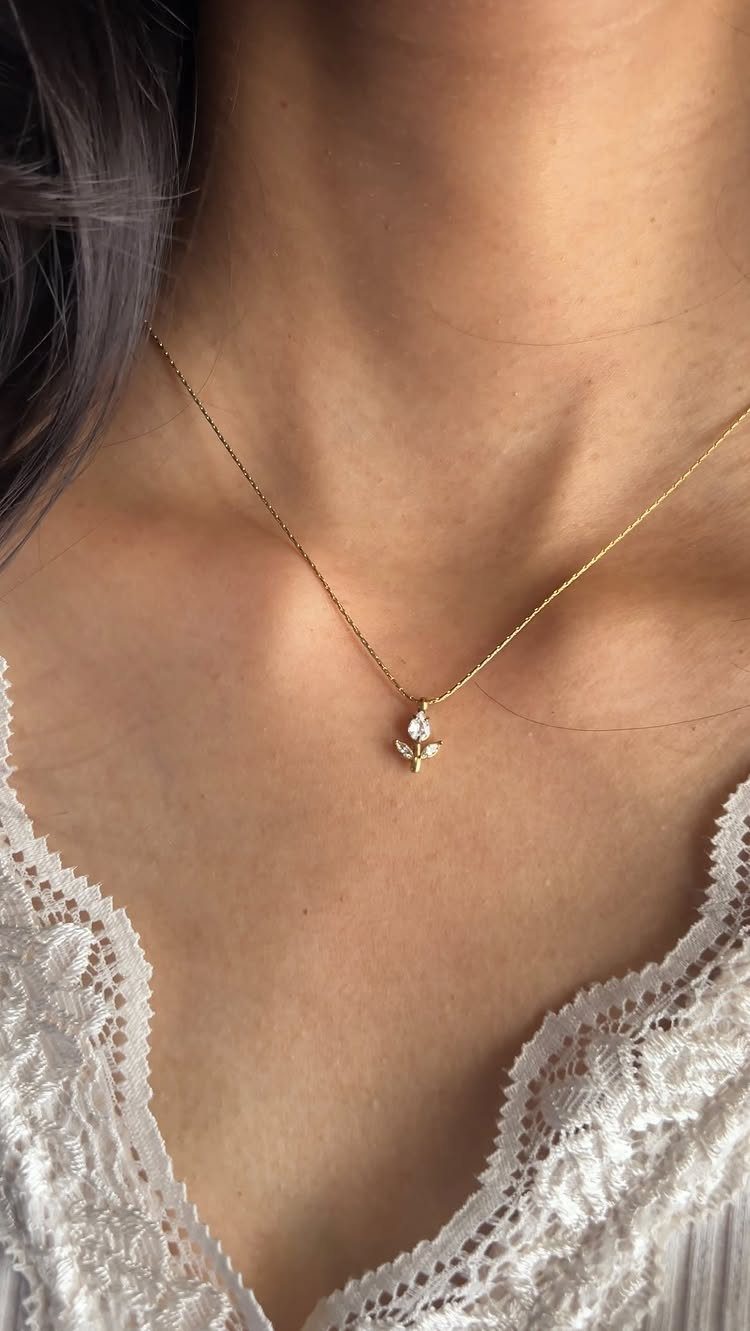 Gold chain necklace with a small sparkling pendant worn on a person's neck