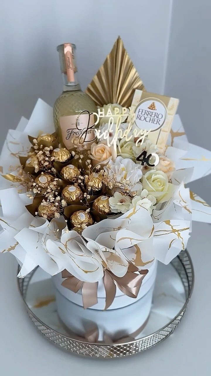 Birthday gift arrangement with champagne, chocolates, white roses, and a 40th birthday topper.