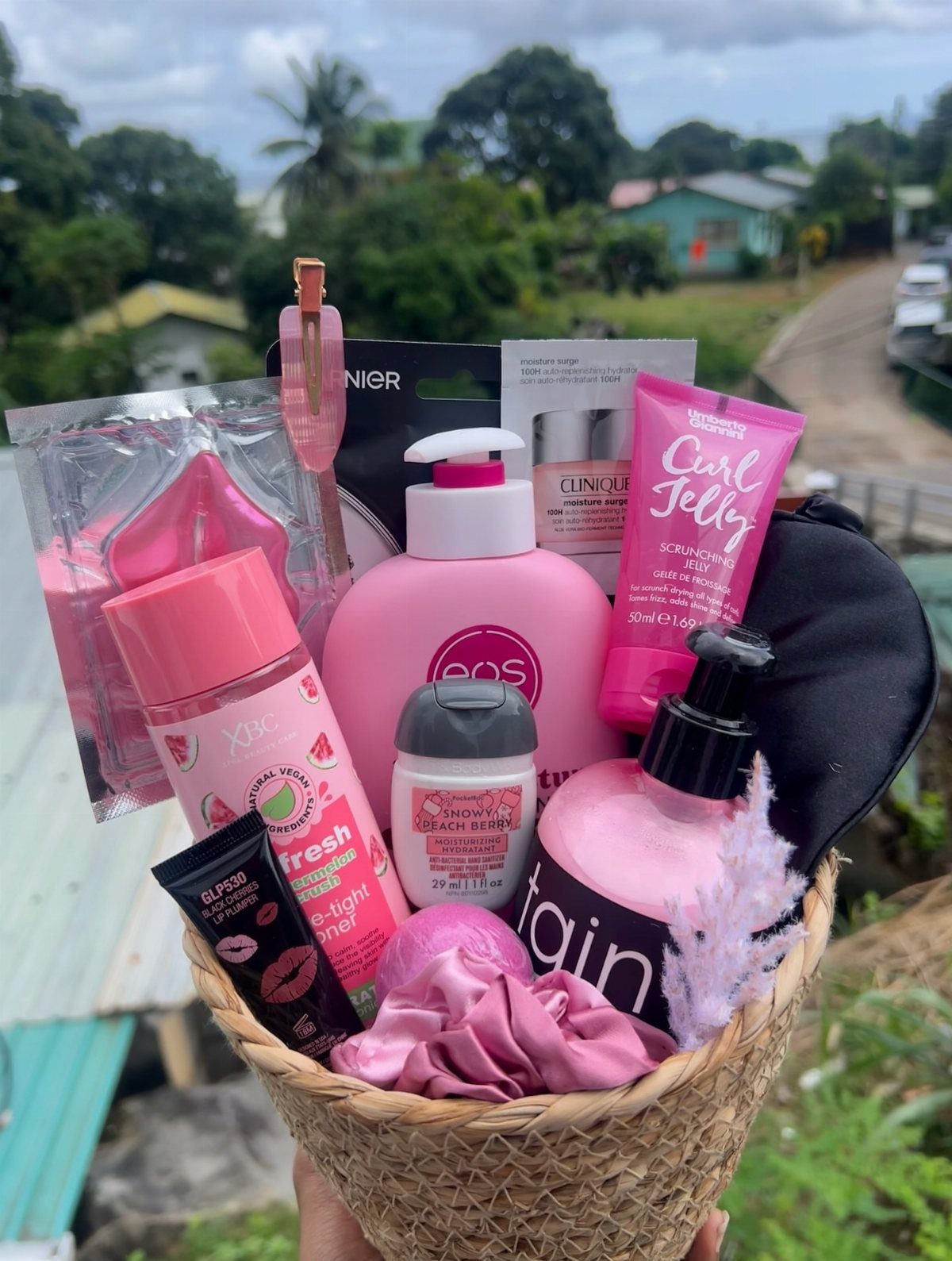 Woven basket filled with pink skincare products, lotions, and a sleep mask.