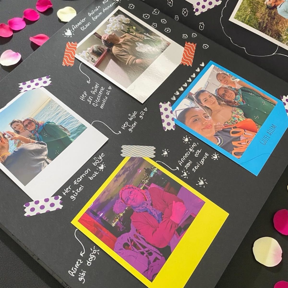 Scrapbook page with printed photos, handwritten notes, and scattered flower petals on black paper.