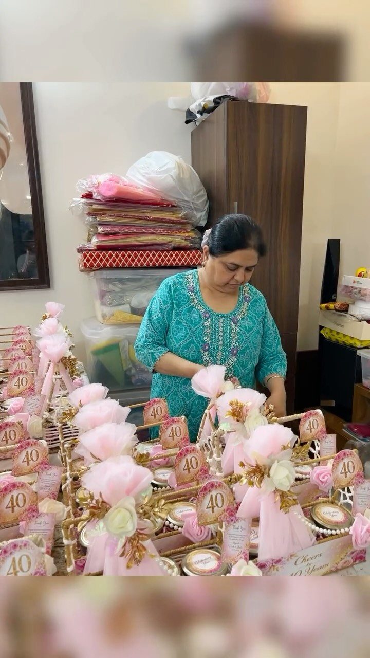 Woman arranging many small pink and gold wrapped gifts with 40 tags.