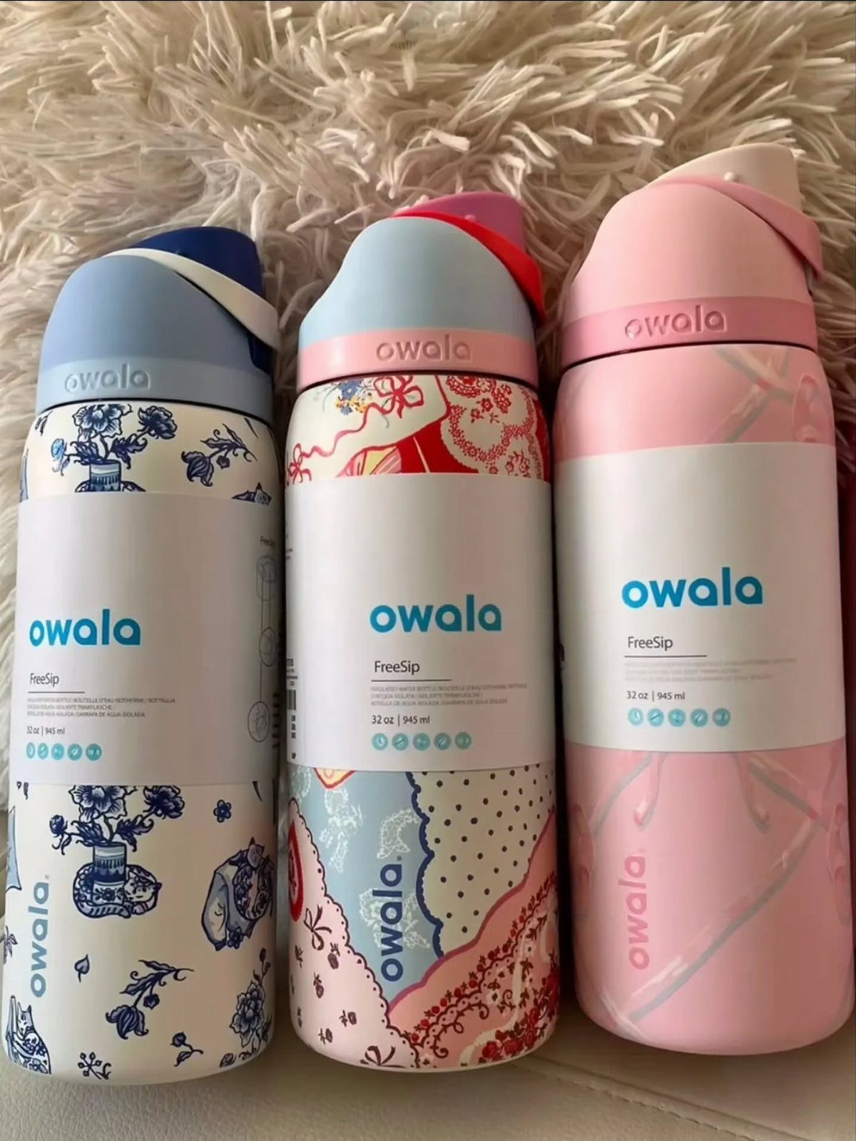 Three Owala FreeSip water bottles in blue floral, multicolored, and pink patterns.