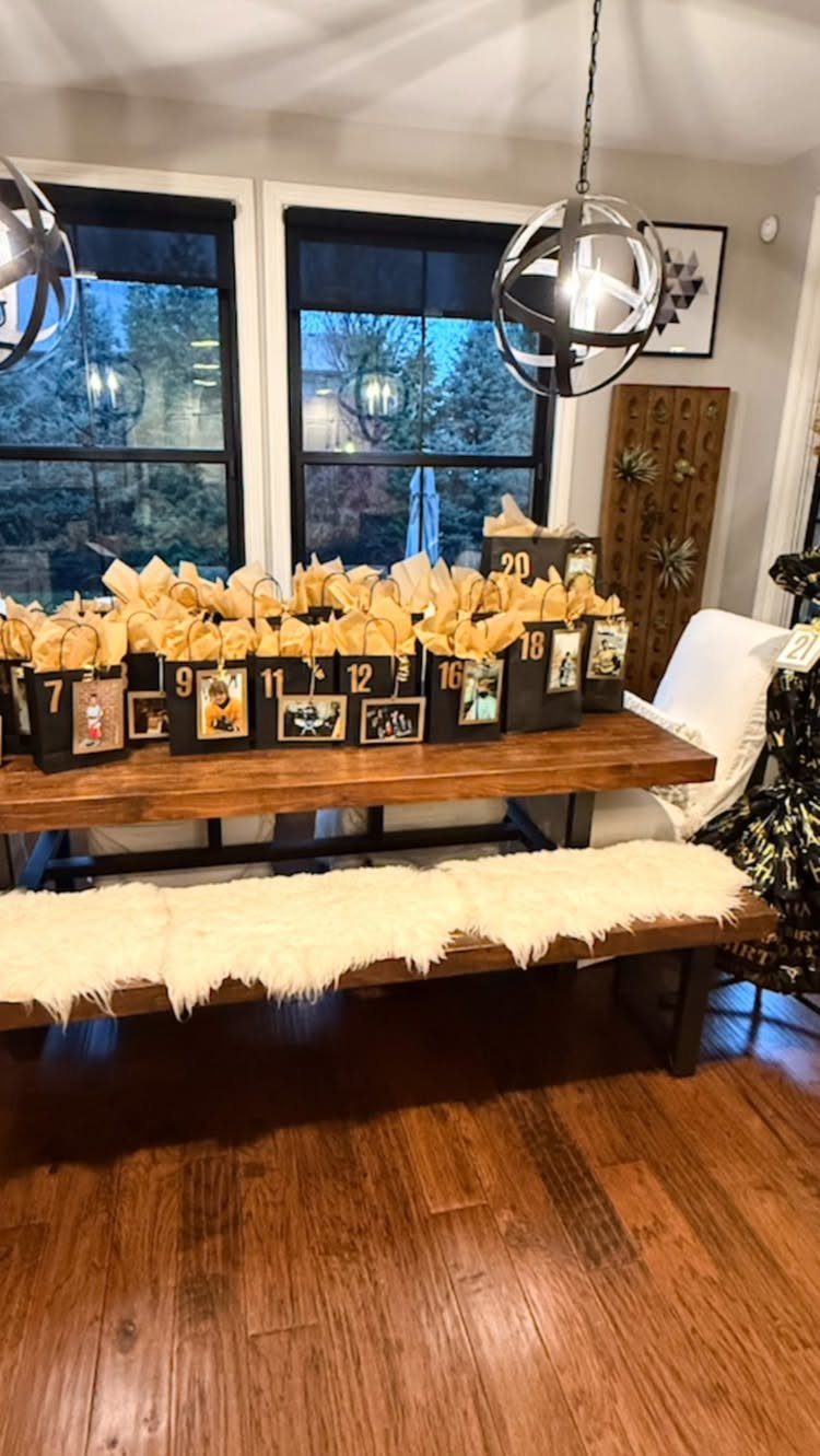 Black gift bags with numbers and photos arranged on a wooden dining table.