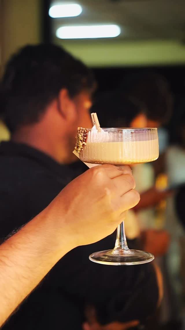 Hand holding a creamy cocktail glass with gold sprinkles on the rim.
