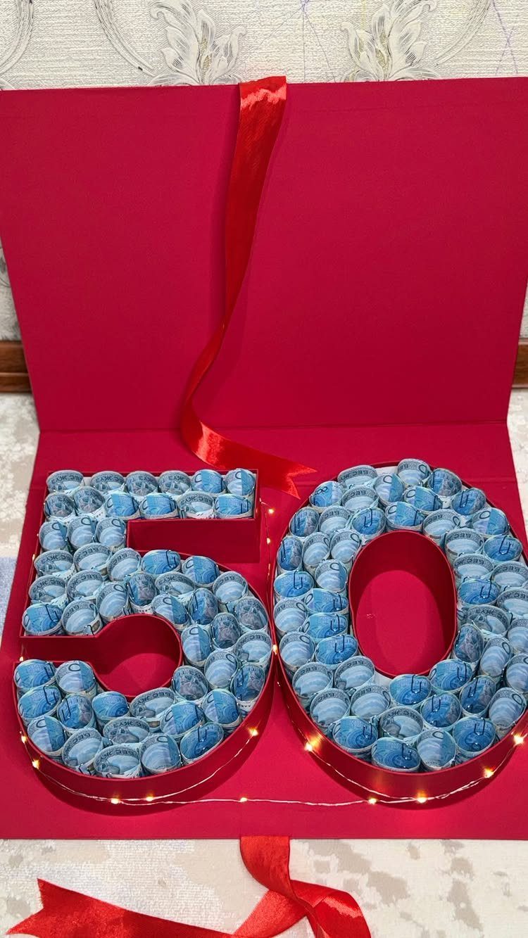Number 50 filled with blue chocolates inside a red gift box with ribbon.