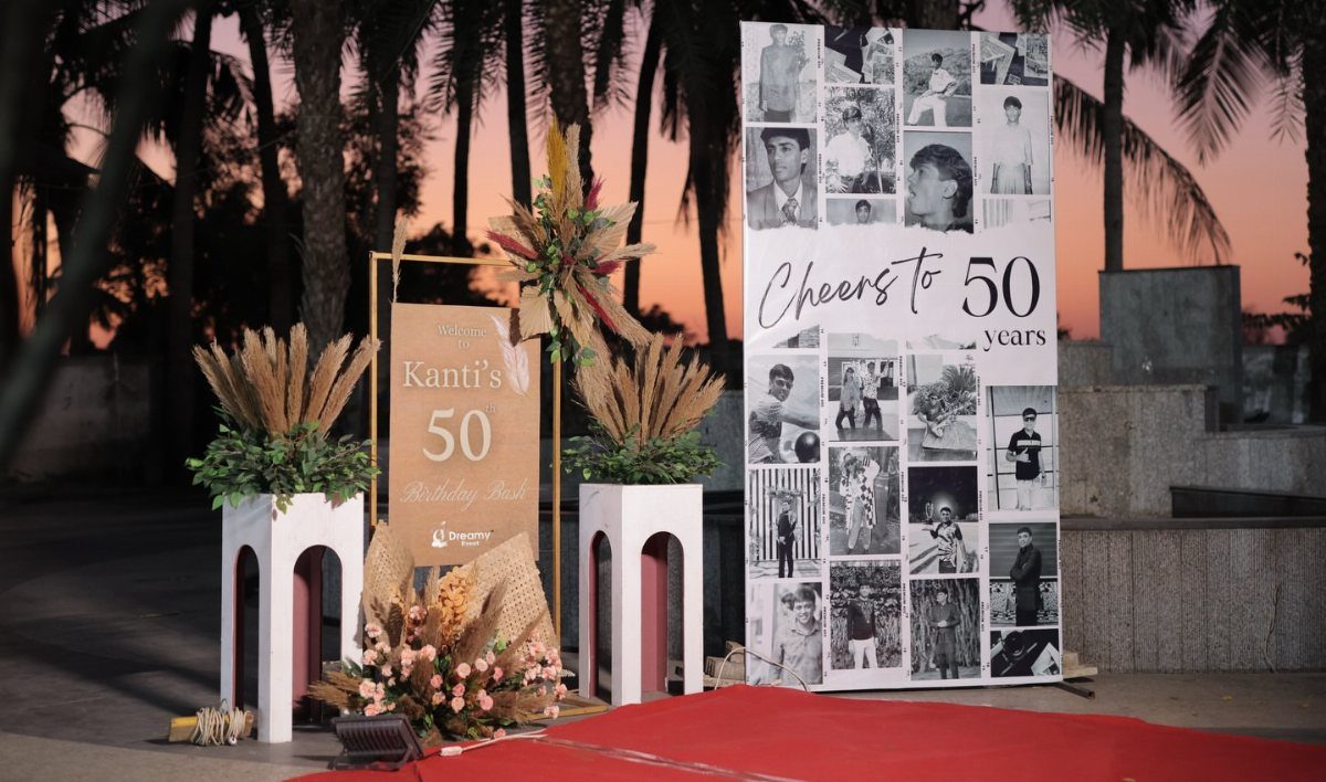 Birthday celebration setup with a 50th anniversary photo collage and floral arrangements outdoors.