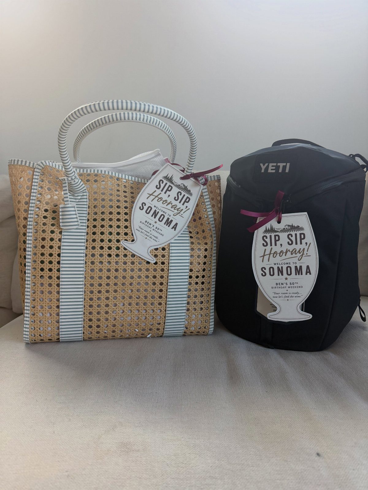 Two wine travel bags, one woven straw and one black insulated, with Sonoma tags.