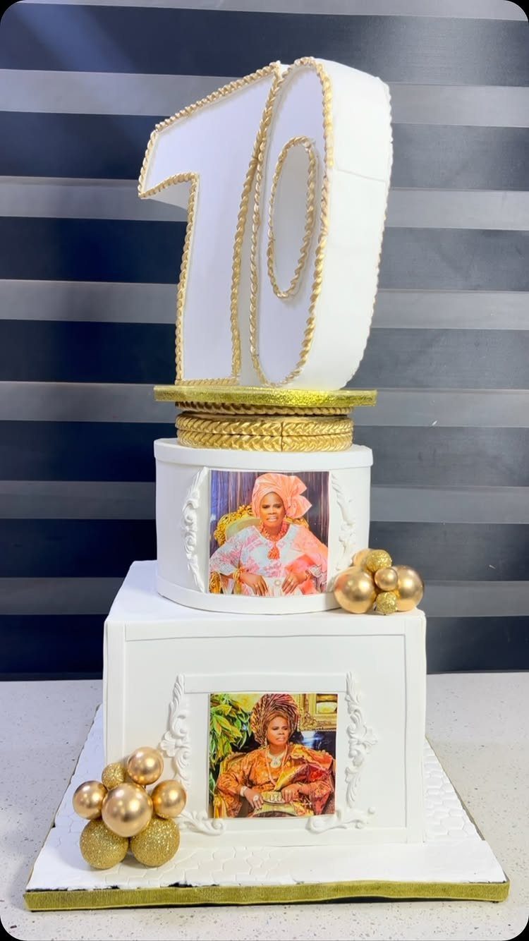 White tiered birthday cake with gold accents, number 70 topper, and woman's photos.
