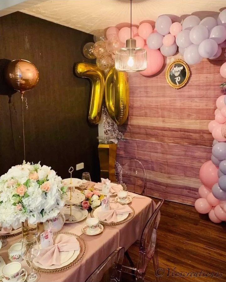 Birthday party table with pink flowers and gold 70 balloons in the background