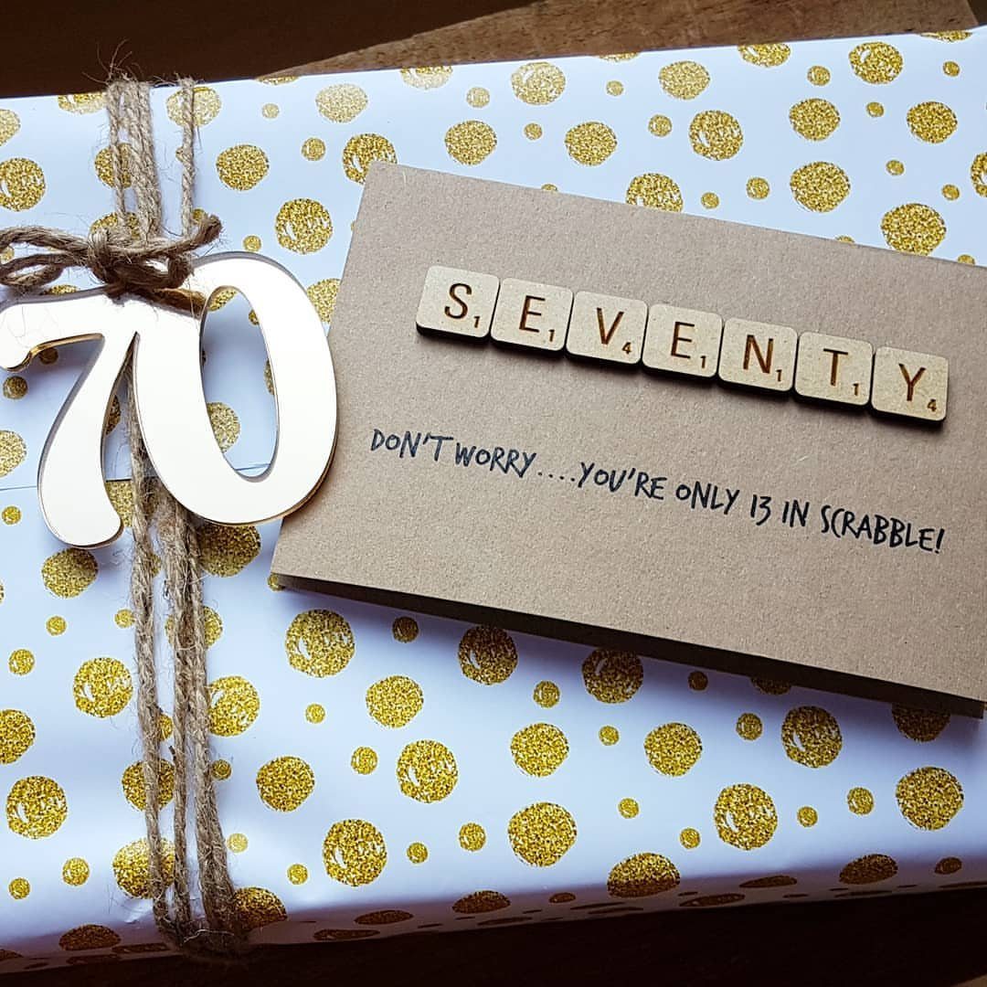 Wrapped gift with gold polka dots, a wooden 70, and a Scrabble card.