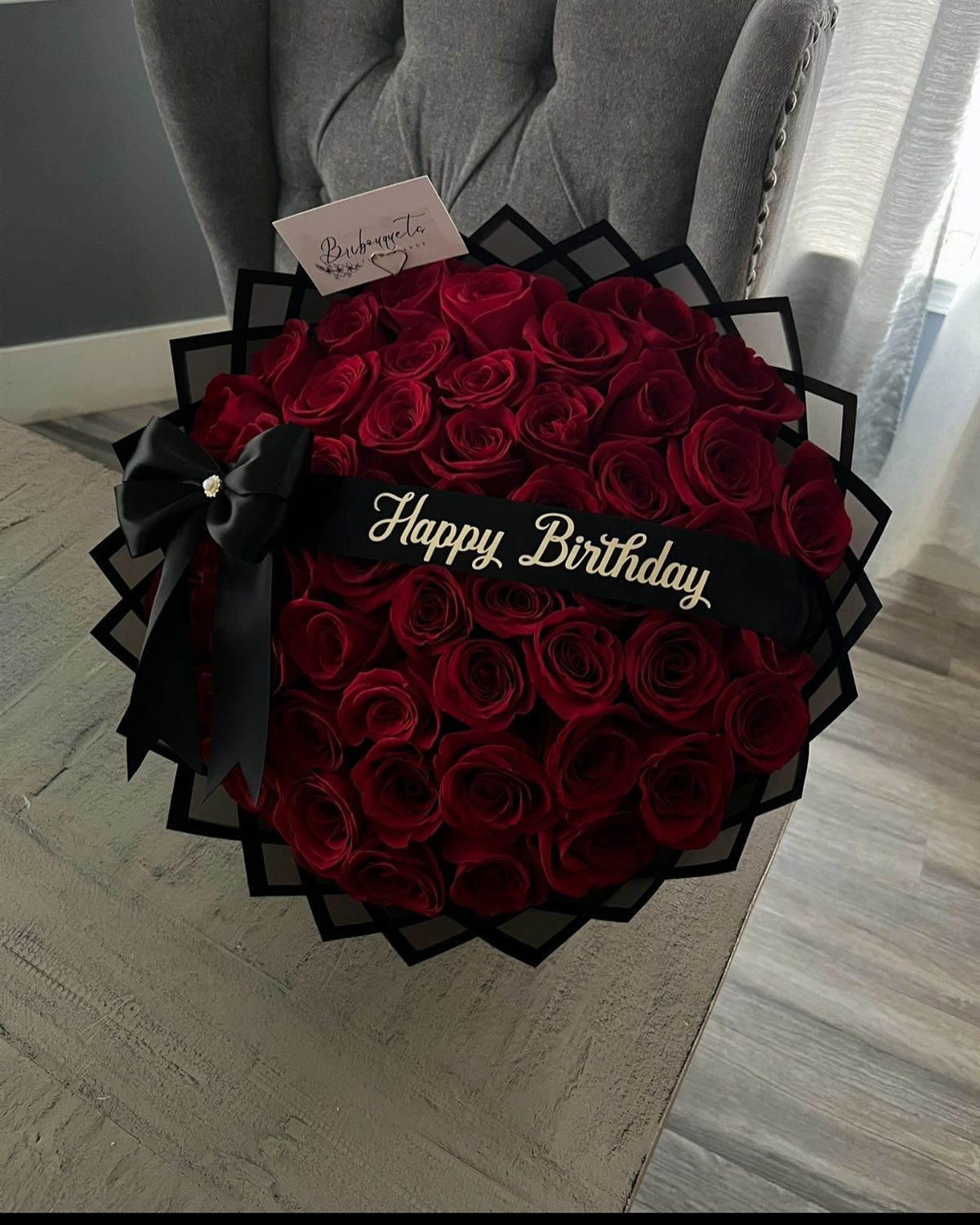 Heart-shaped bouquet of red roses with a black Happy Birthday ribbon and card.
