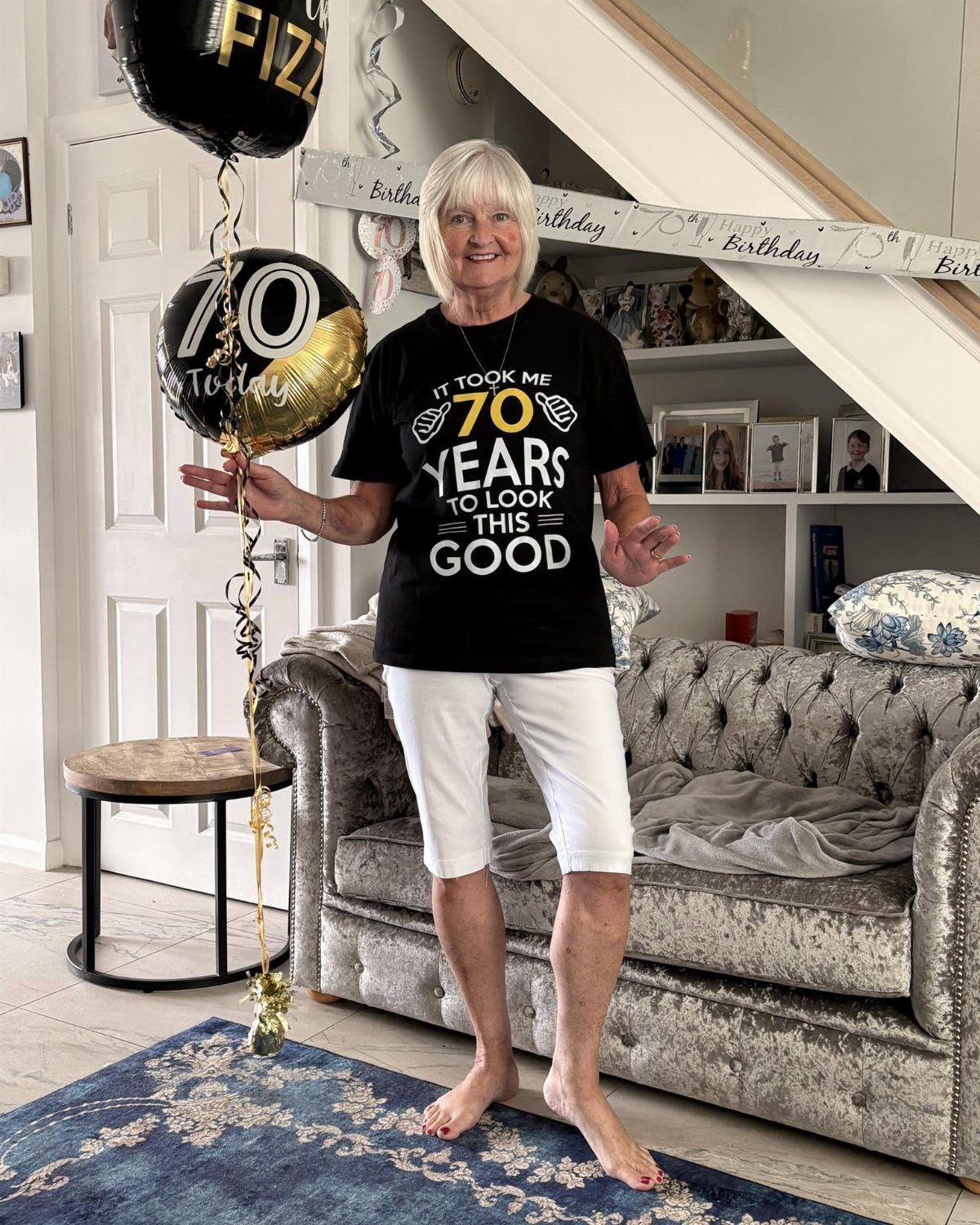 Older woman celebrating her 70th birthday with themed balloons and a t-shirt.
