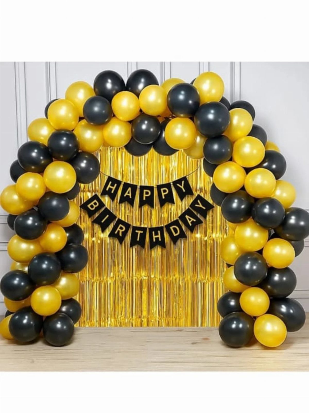 Gold and black balloon arch with a Happy Birthday banner and gold curtain.