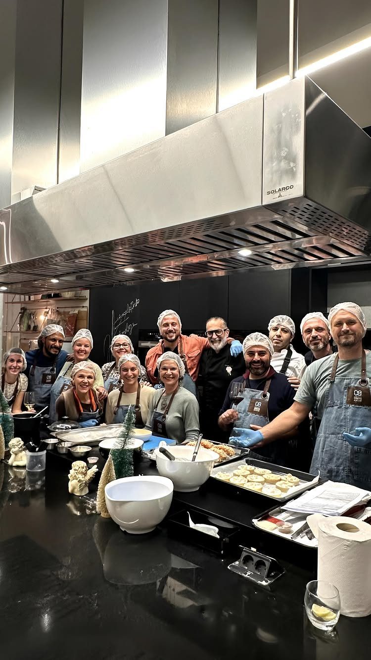 Group of people in aprons and hairnets posing in a professional kitchen.