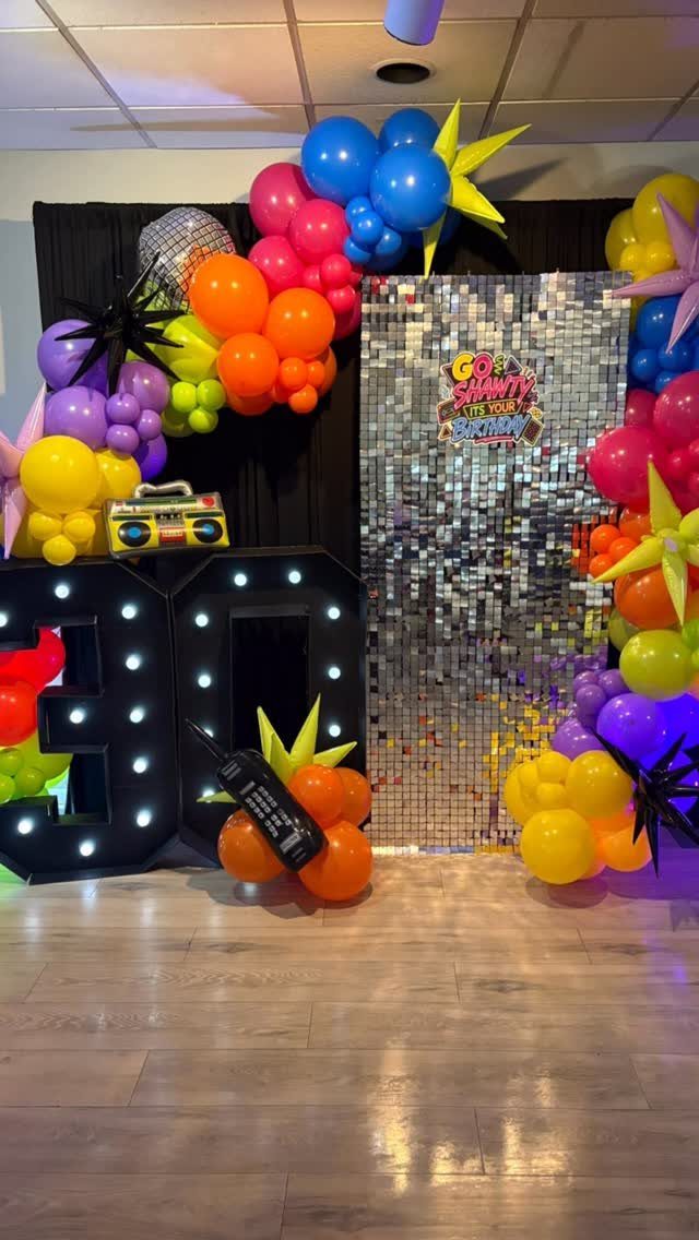 Colorful 90s themed party setup with neon balloons, light-up 30 numbers, and boombox.