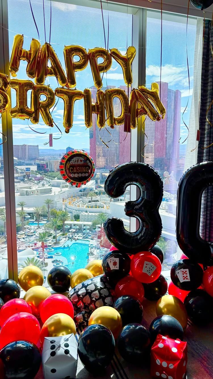 Gold and black birthday balloons with the number 30 overlooking a city skyline.