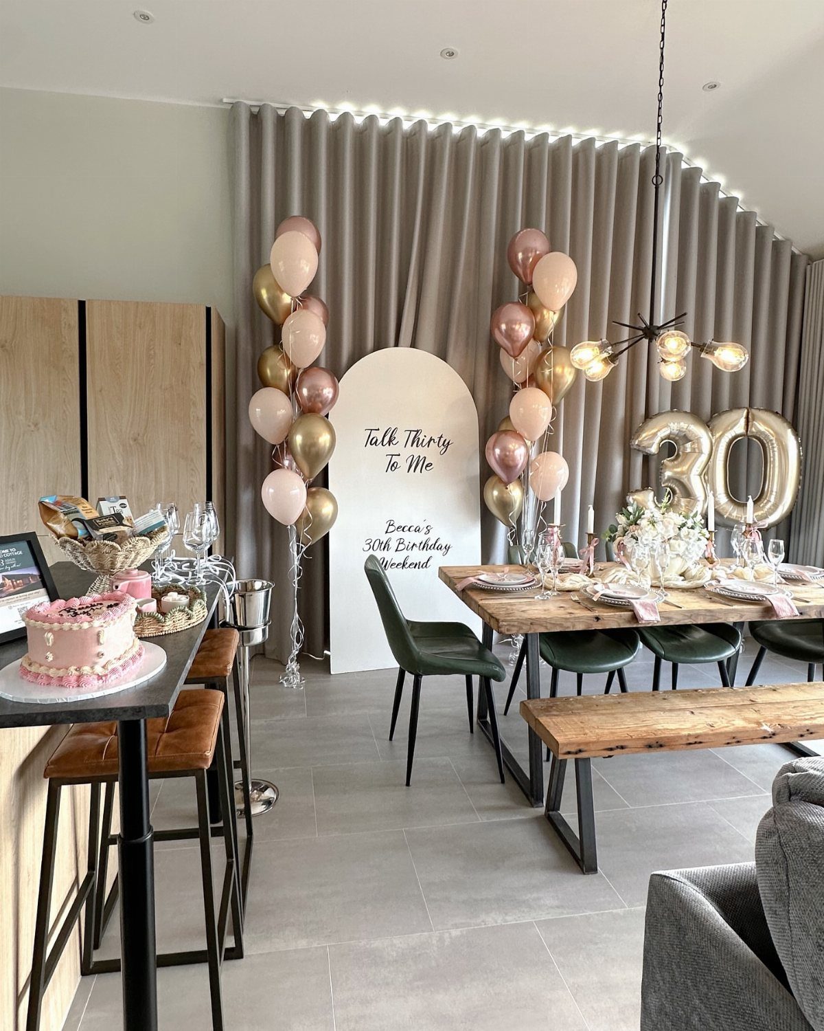 Birthday party decorations with gold balloons, a pink cake, and a 30th birthday sign.