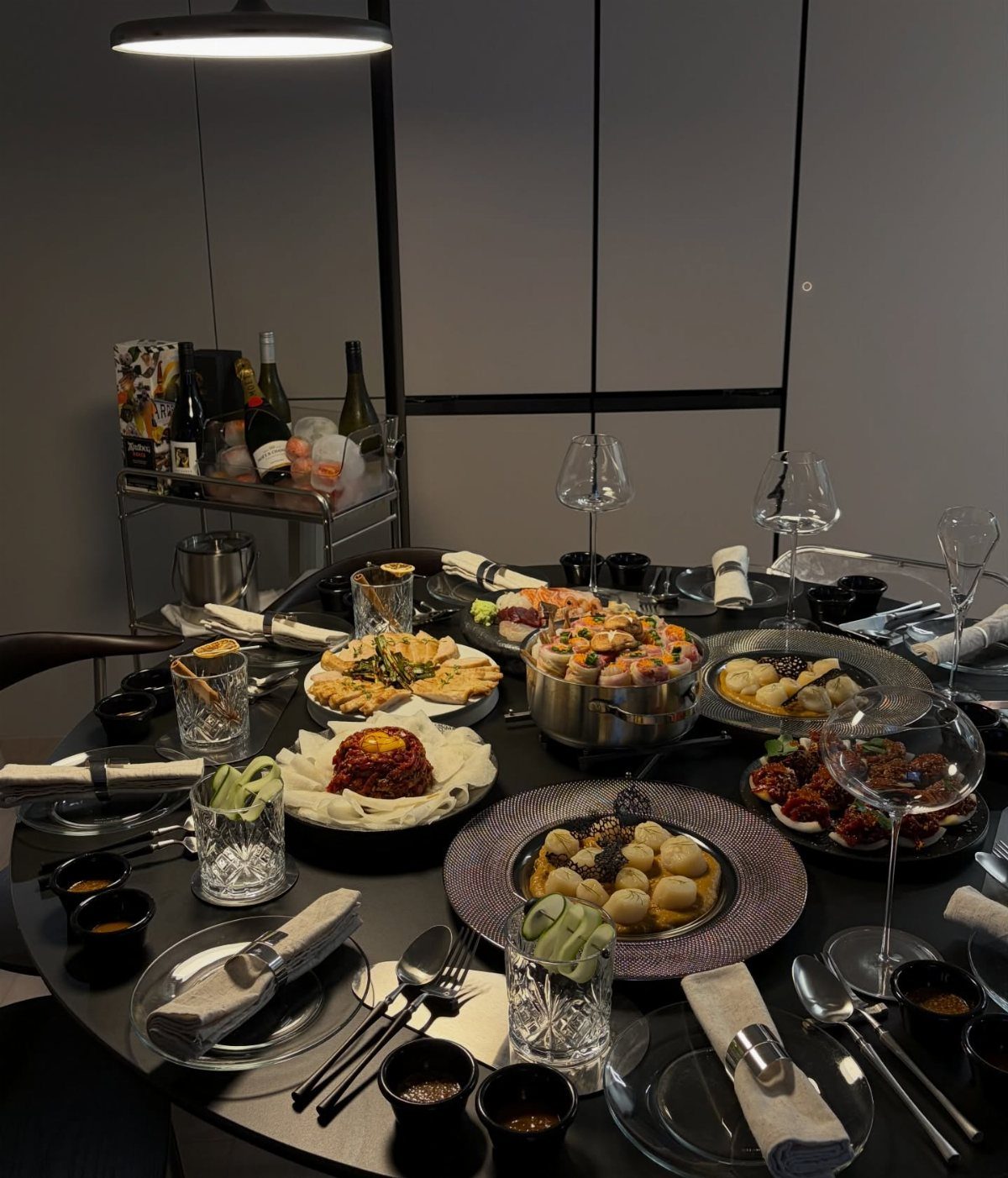 Gourmet dinner party spread with multiple plated dishes on a black round table.