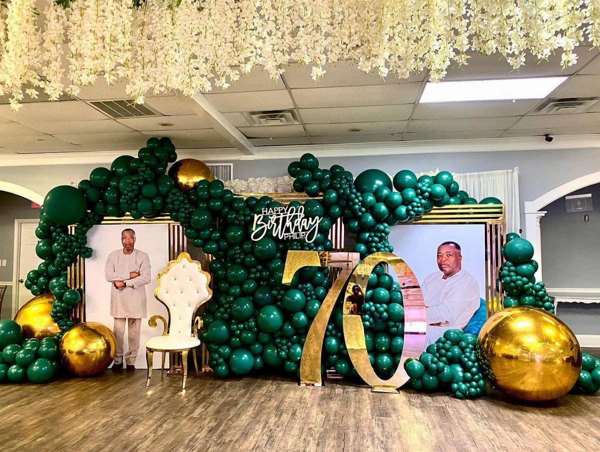 Green and gold balloon arch with gold number 70 for a birthday party.