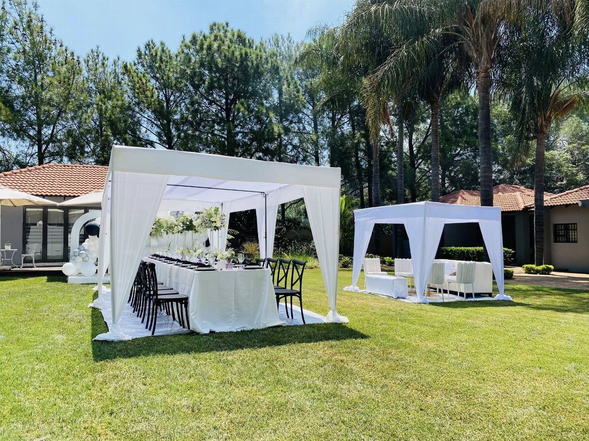 White outdoor event tents with dining and lounge setups on a grassy lawn