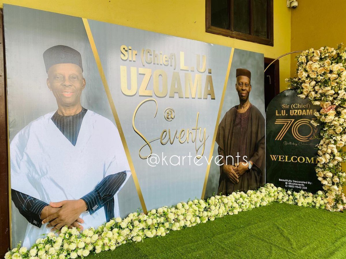 Celebratory 70th birthday backdrop with portraits, gold lettering, and white floral arrangements.