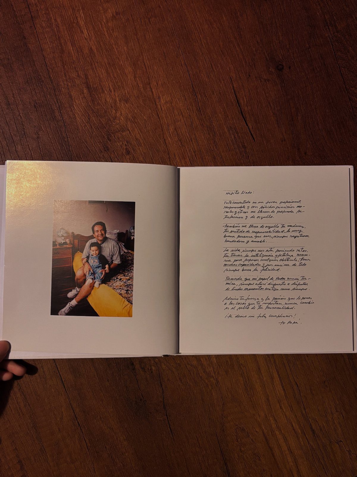 Open photo book with a vintage family photograph and handwritten notes on wood.