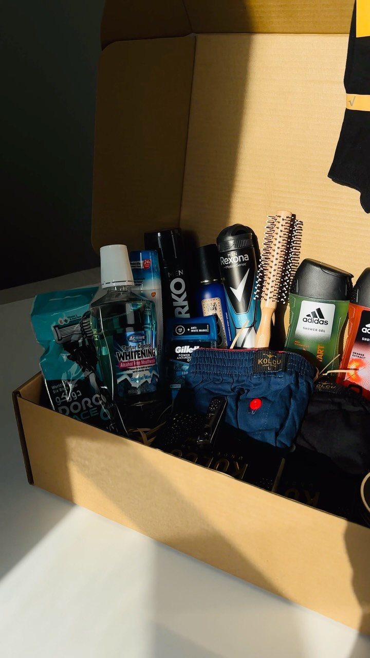 Grooming kit in a cardboard box with toiletries, hairbrush, and blue underwear.