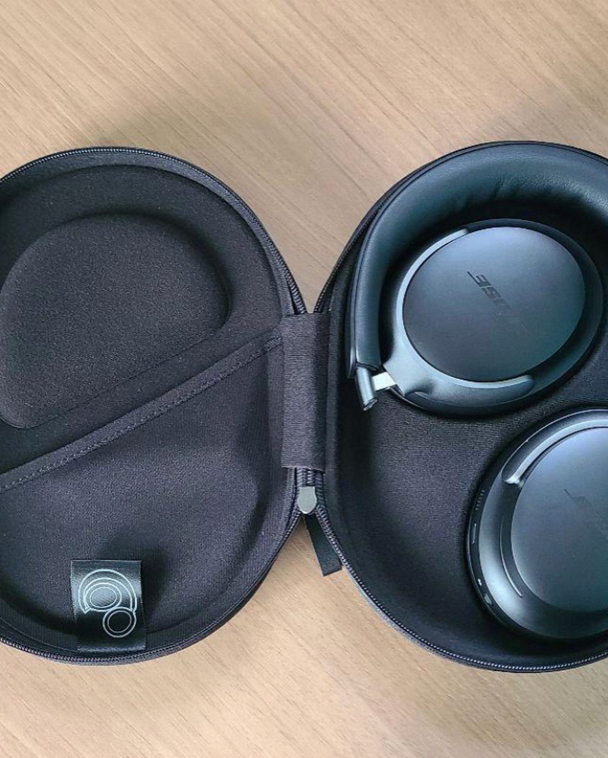 Black over-ear headphones inside a black protective case on a wooden table