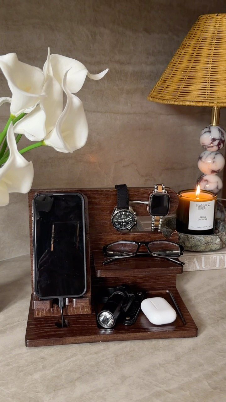 Wooden valet tray holding a wristwatch, smartwatch, smartphone, and other personal accessories.