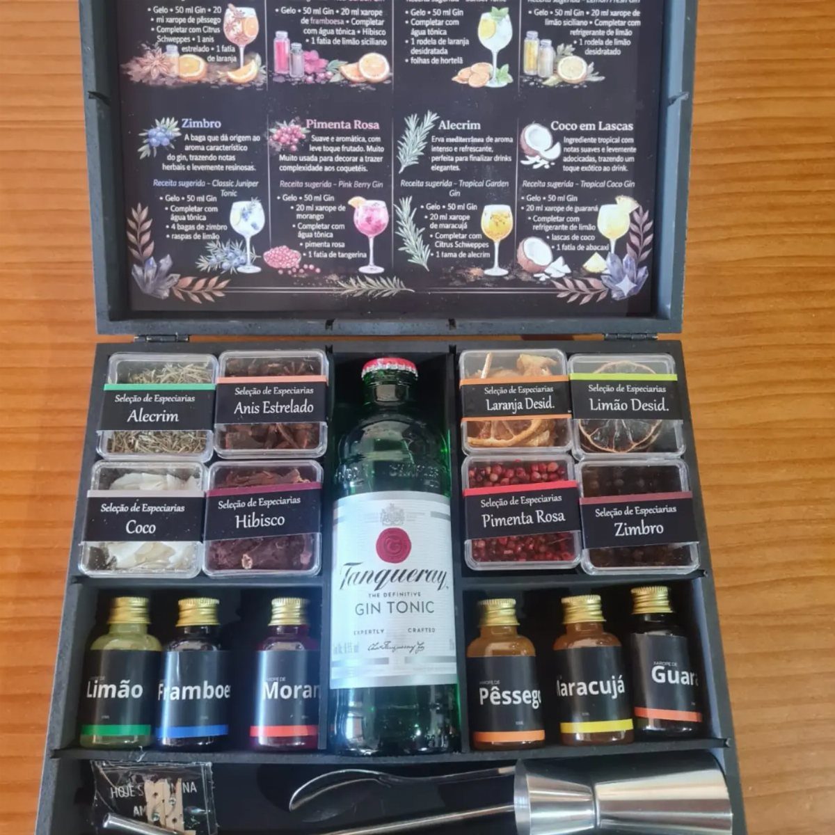 Cocktail kit with gin tonic bottle, flavored syrups, and botanical garnishes in a box.