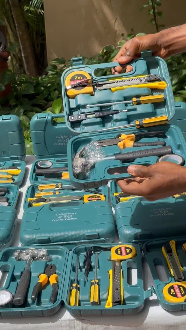 Teal tool kits with yellow and black hand tools arranged on a white table.