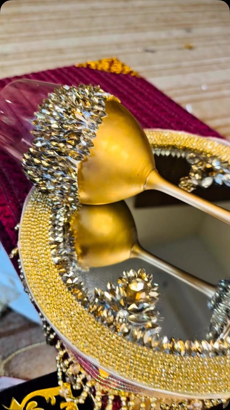 Gold champagne flutes with crystal-encrusted rims resting on a mirrored gold tray
