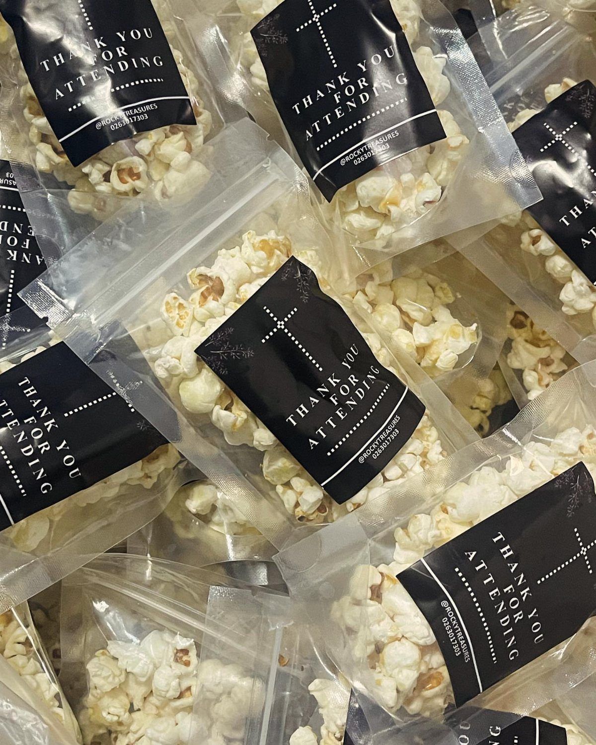 Clear plastic bags of popcorn with black thank you labels as party favors.