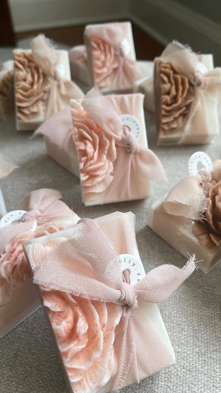 Handmade floral soaps wrapped in peach sheer fabric with small white tags.