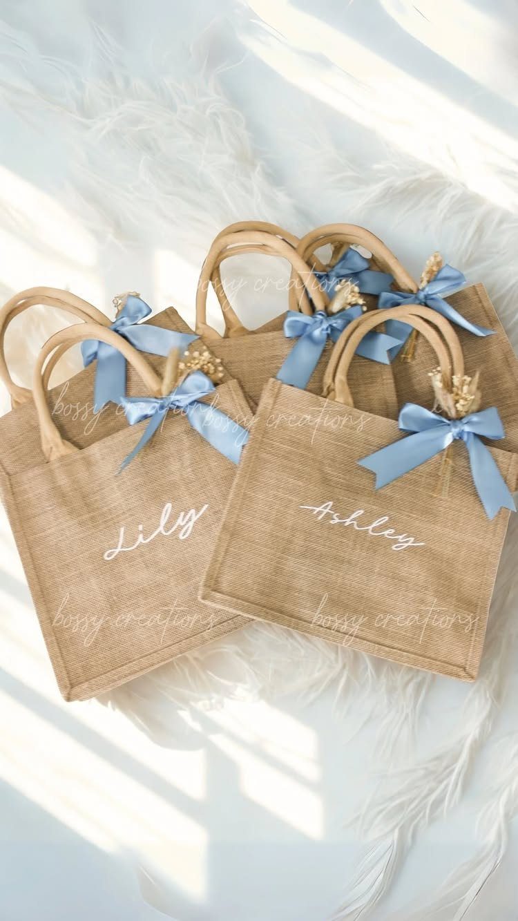 Burlap gift bags with blue ribbons and white names on white fur.