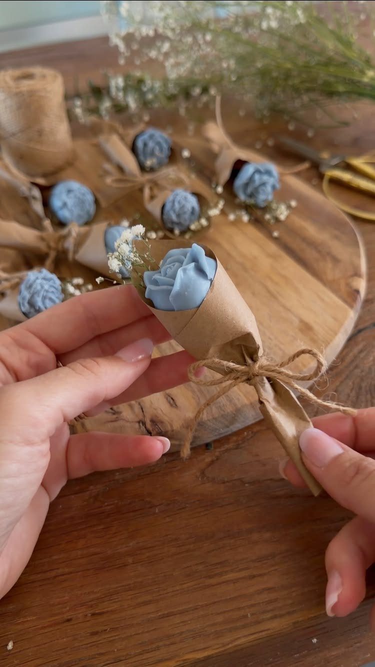 Small blue roses wrapped in brown paper and twine as party favors.