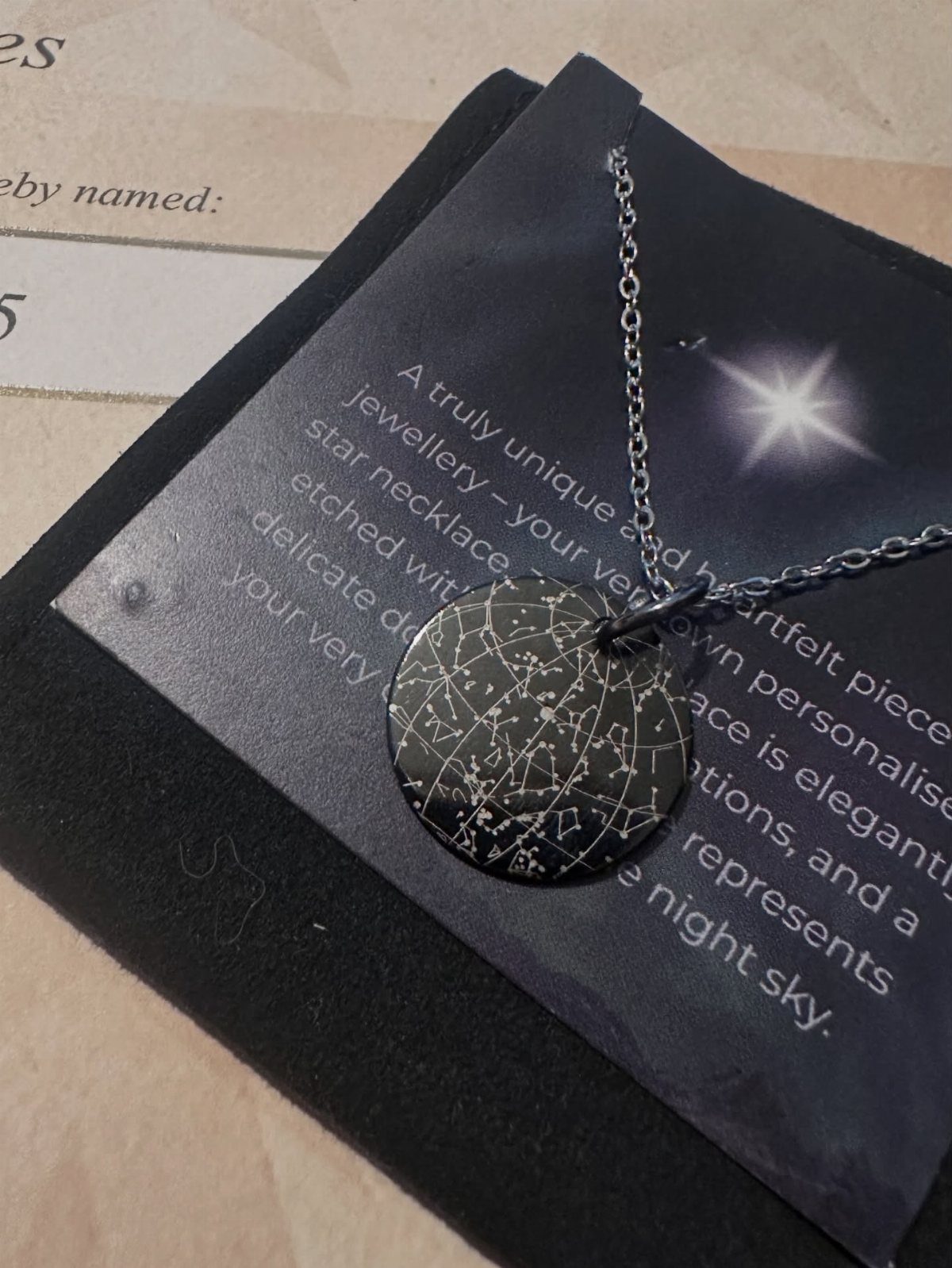 Silver star map necklace resting on a black descriptive jewelry card