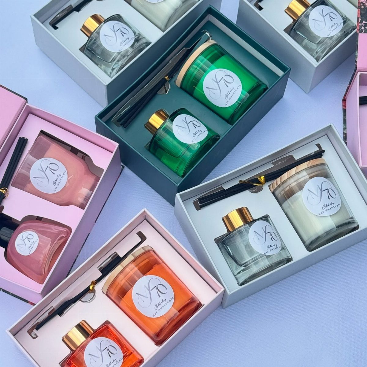Gift boxes containing perfume bottles, scented candles, and pens with 70th birthday labels.