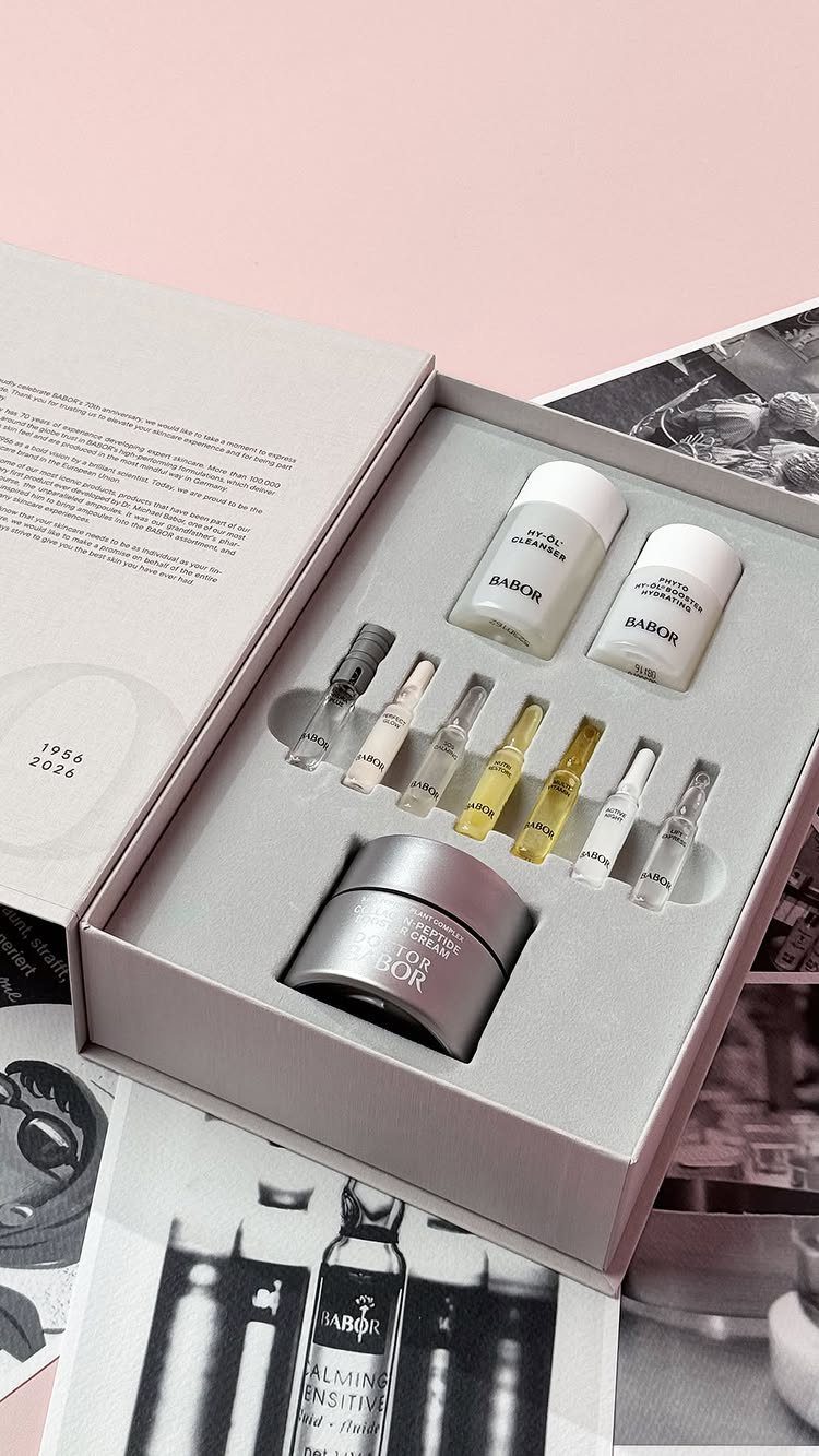 Luxury skincare set with cream, bottles, and ampoules in a grey gift box.