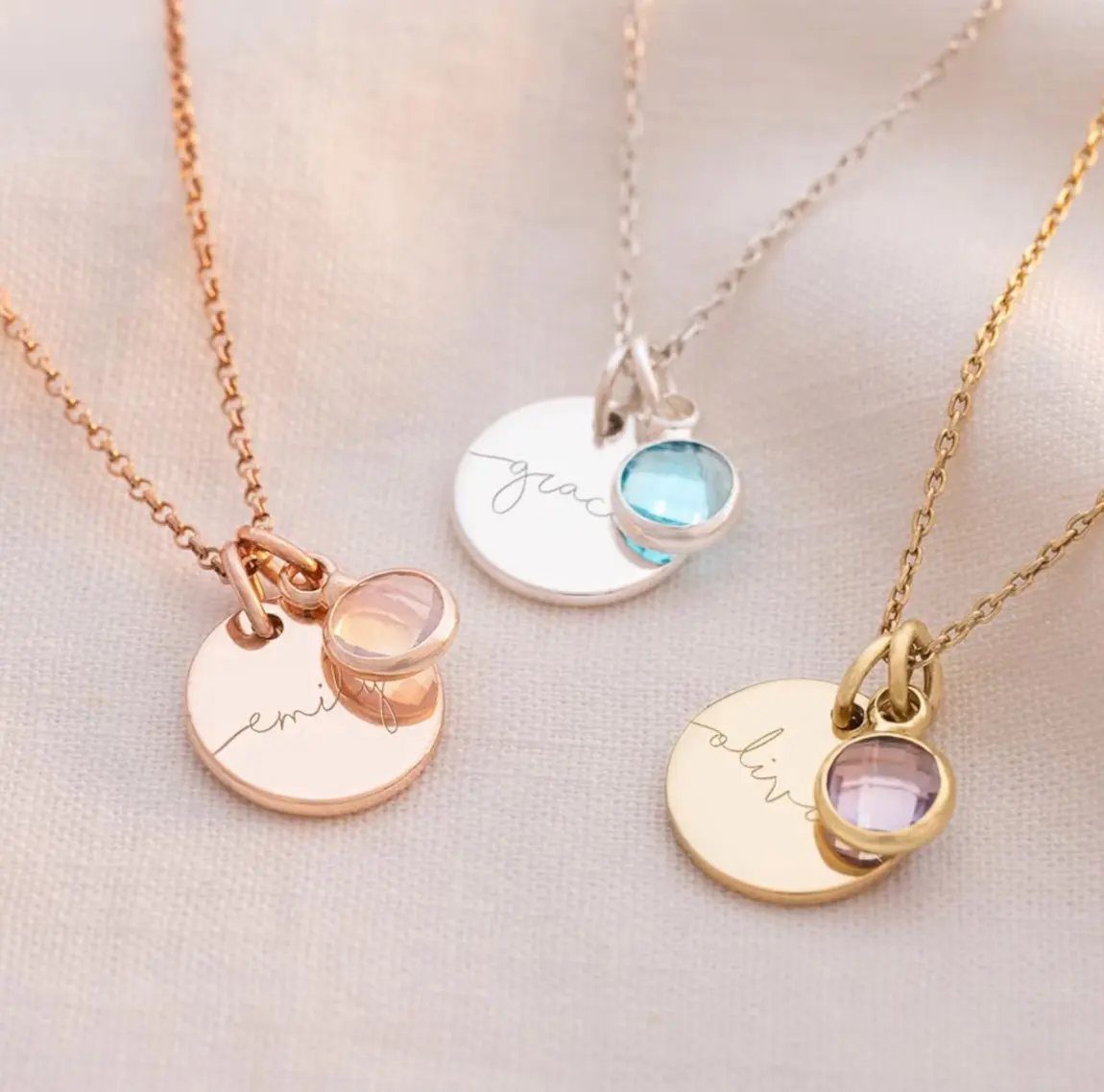 Three personalized birthstone necklaces with name pendants in gold, silver, and rose gold.