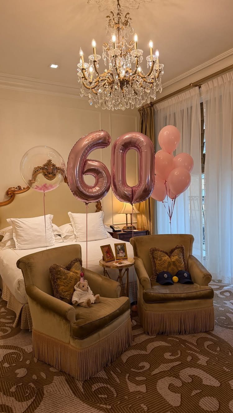 Rose-gold 60 balloons and pink balloons in a luxury hotel room with chandelier.