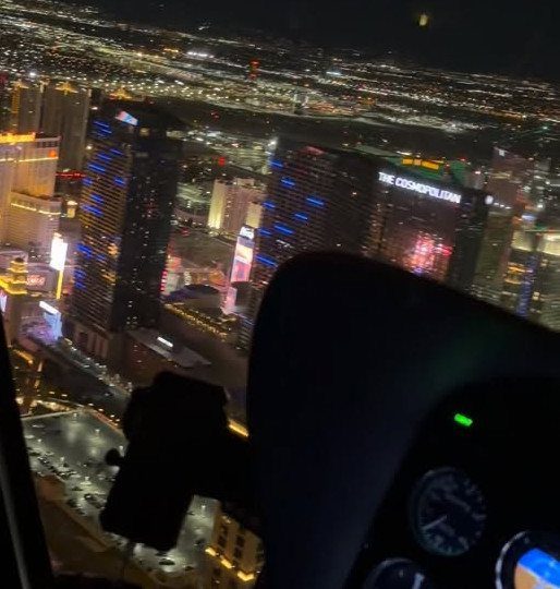 Las Vegas Strip at night viewed from a helicopter cockpit window.